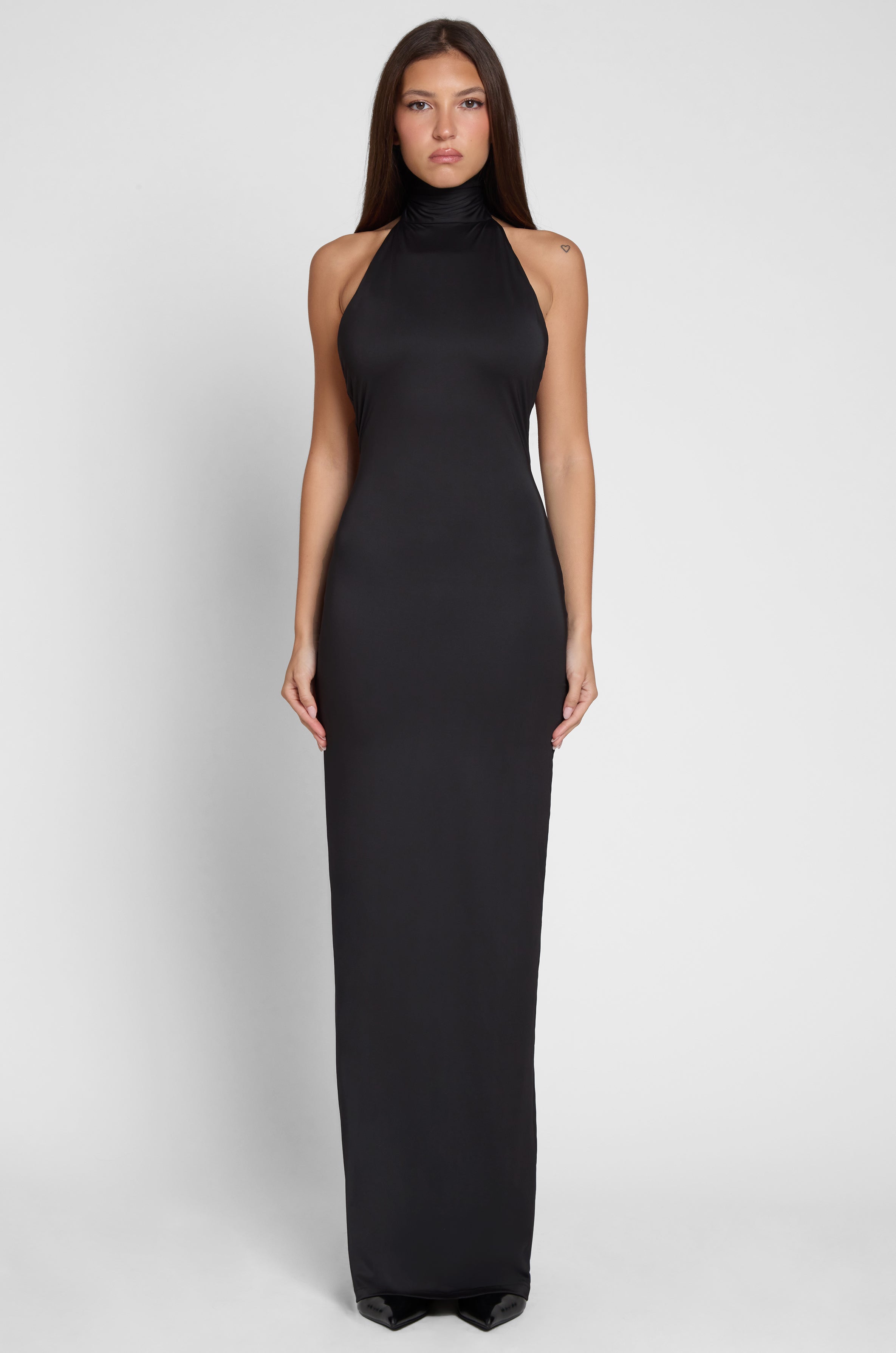 Model is wearing Alaia Drape Maxi Dress Black, front view.