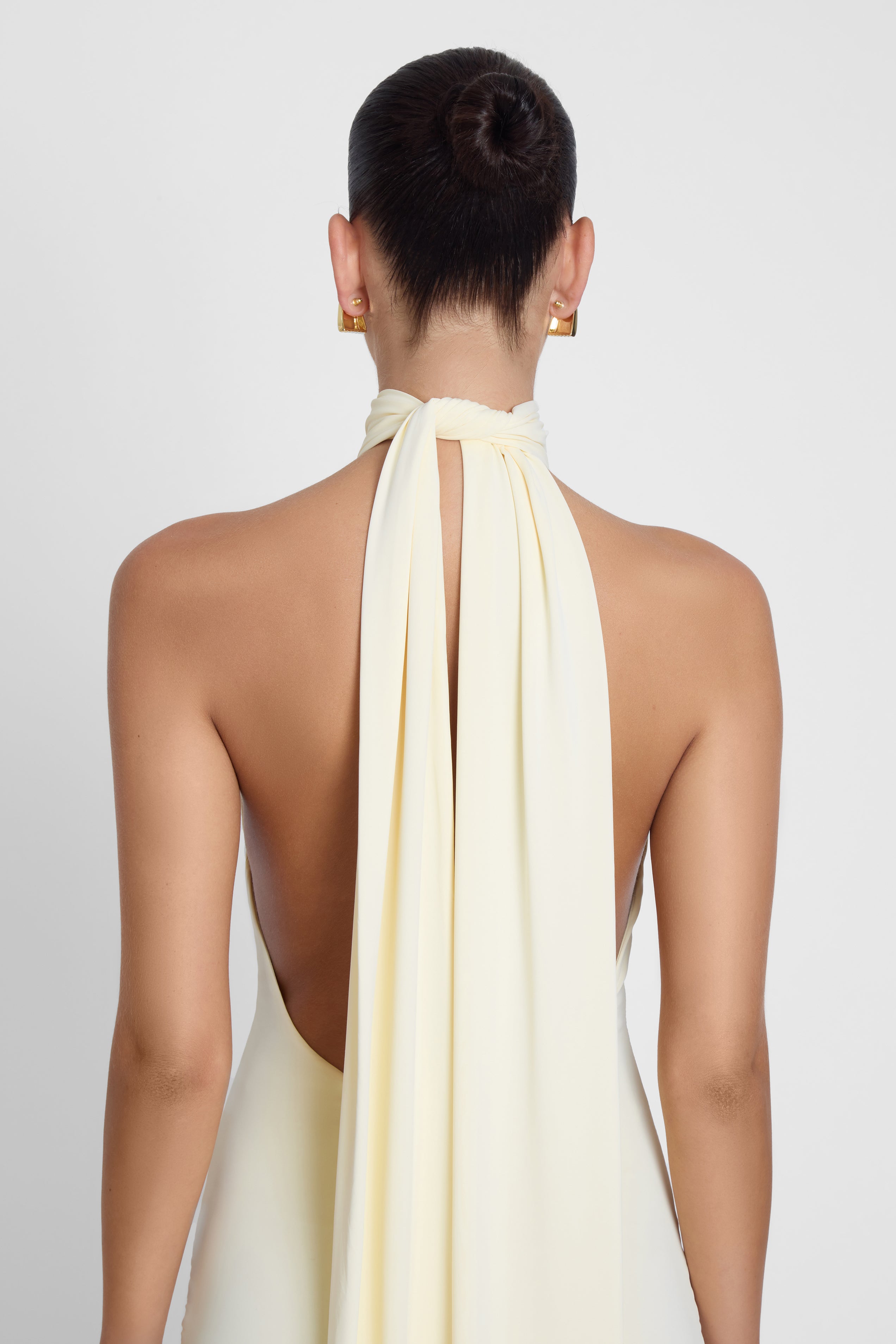 Model is wearing Alaia Drape Maxi Dress Yellow, back view.