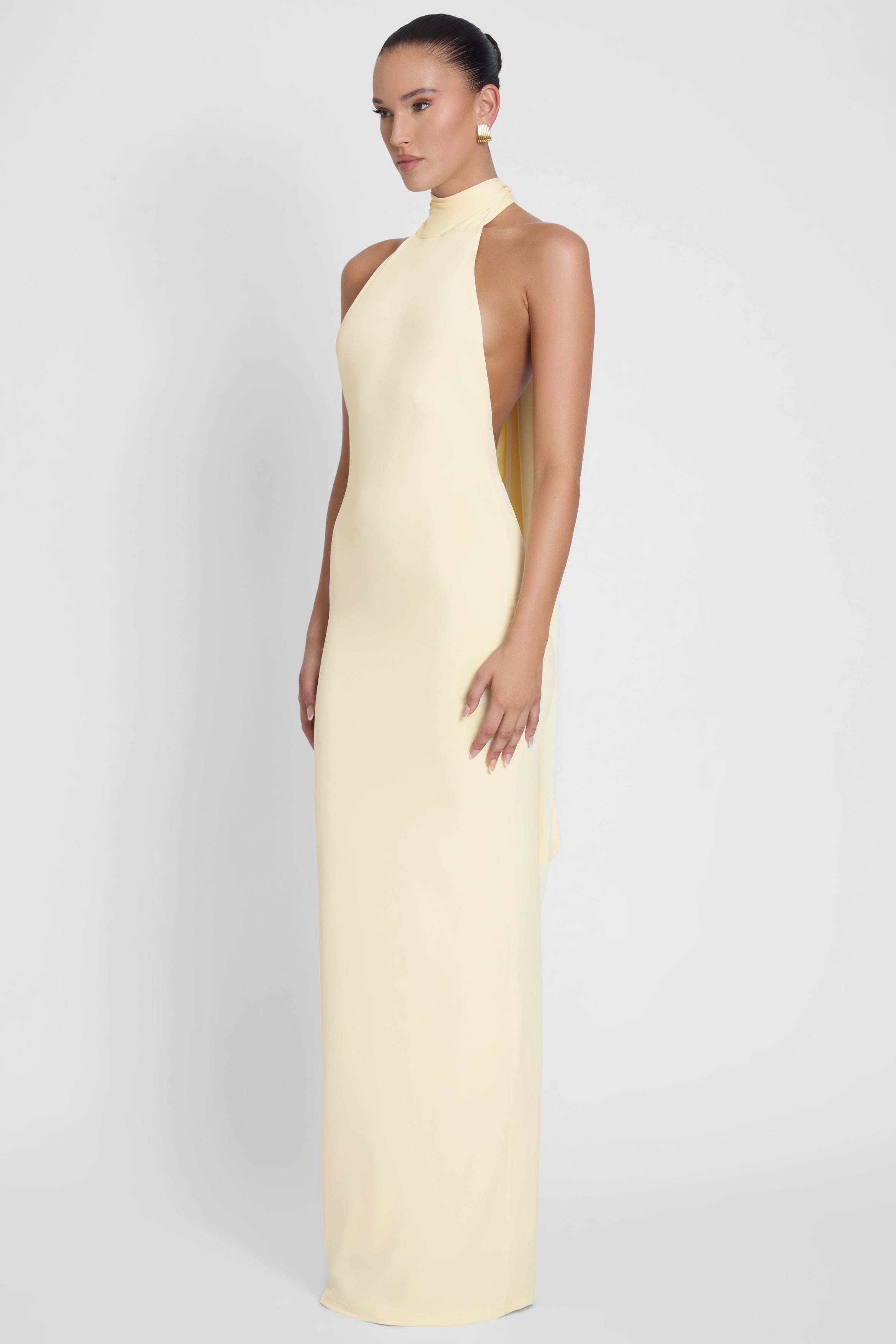 Model is wearing Alaia Drape Maxi Dress Yellow, side view.