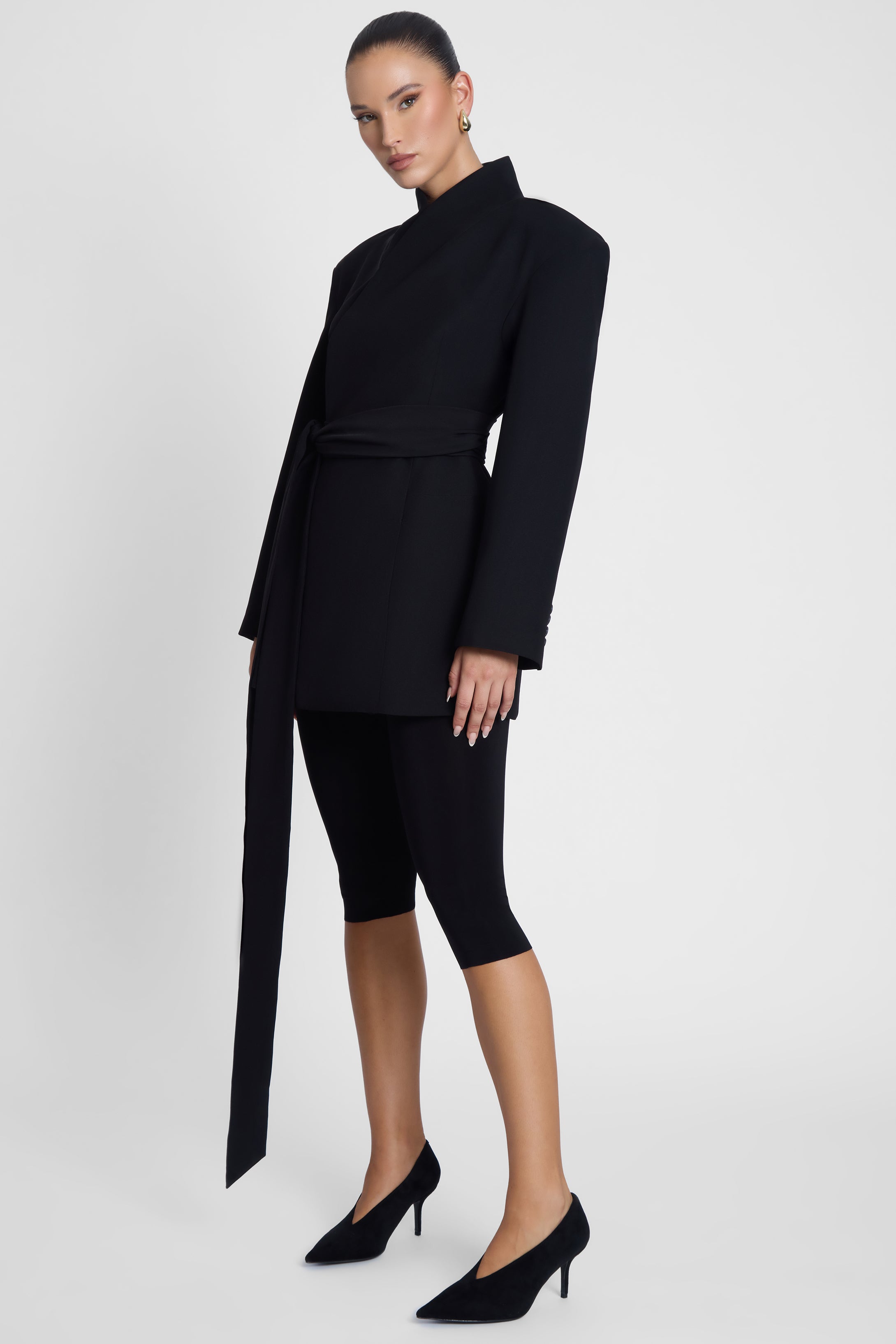 Model is wearing Cairo Hourglass Belted Coat Black, side view.