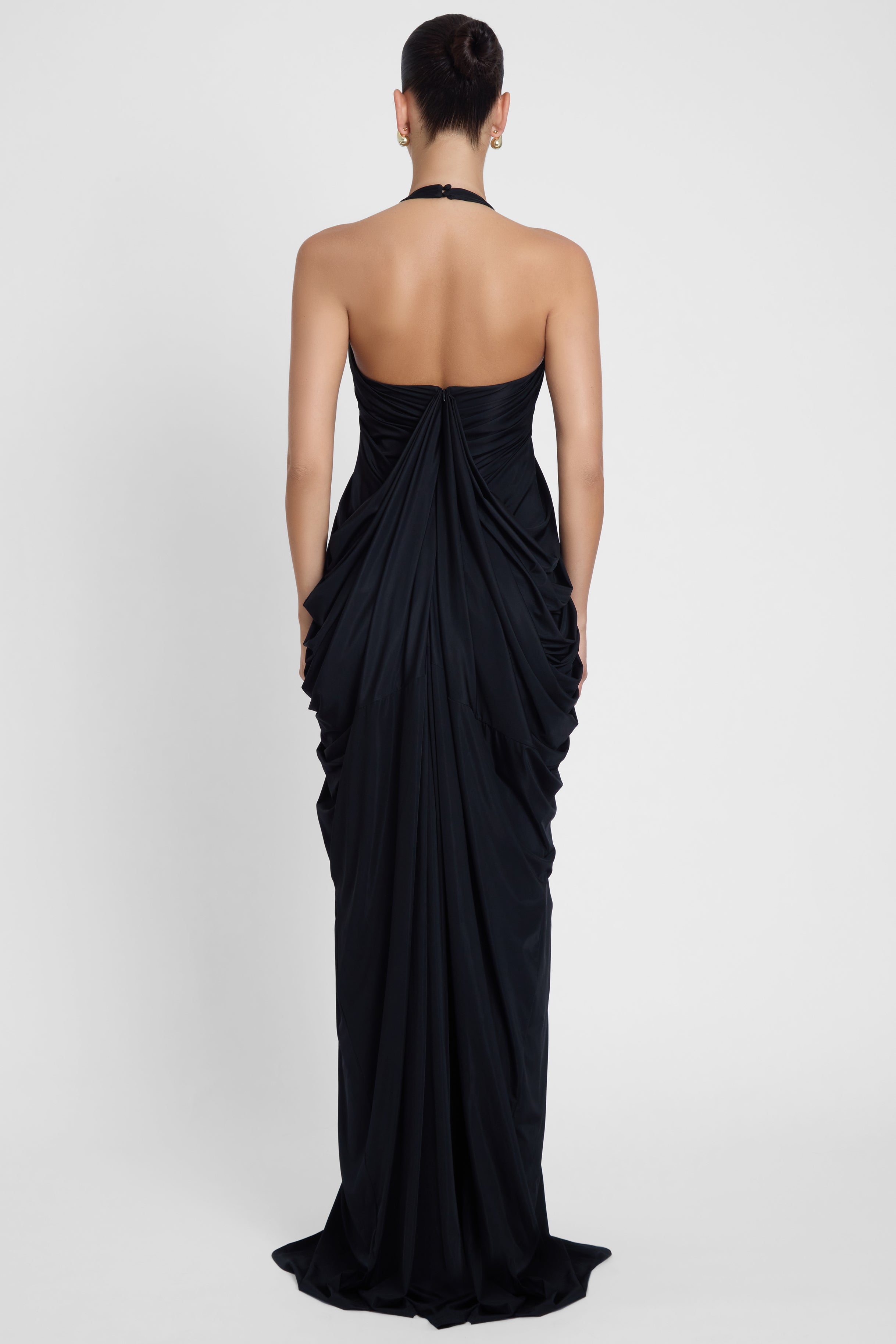 Model is wearing Cascade Drape Gown Black in Black, back view.