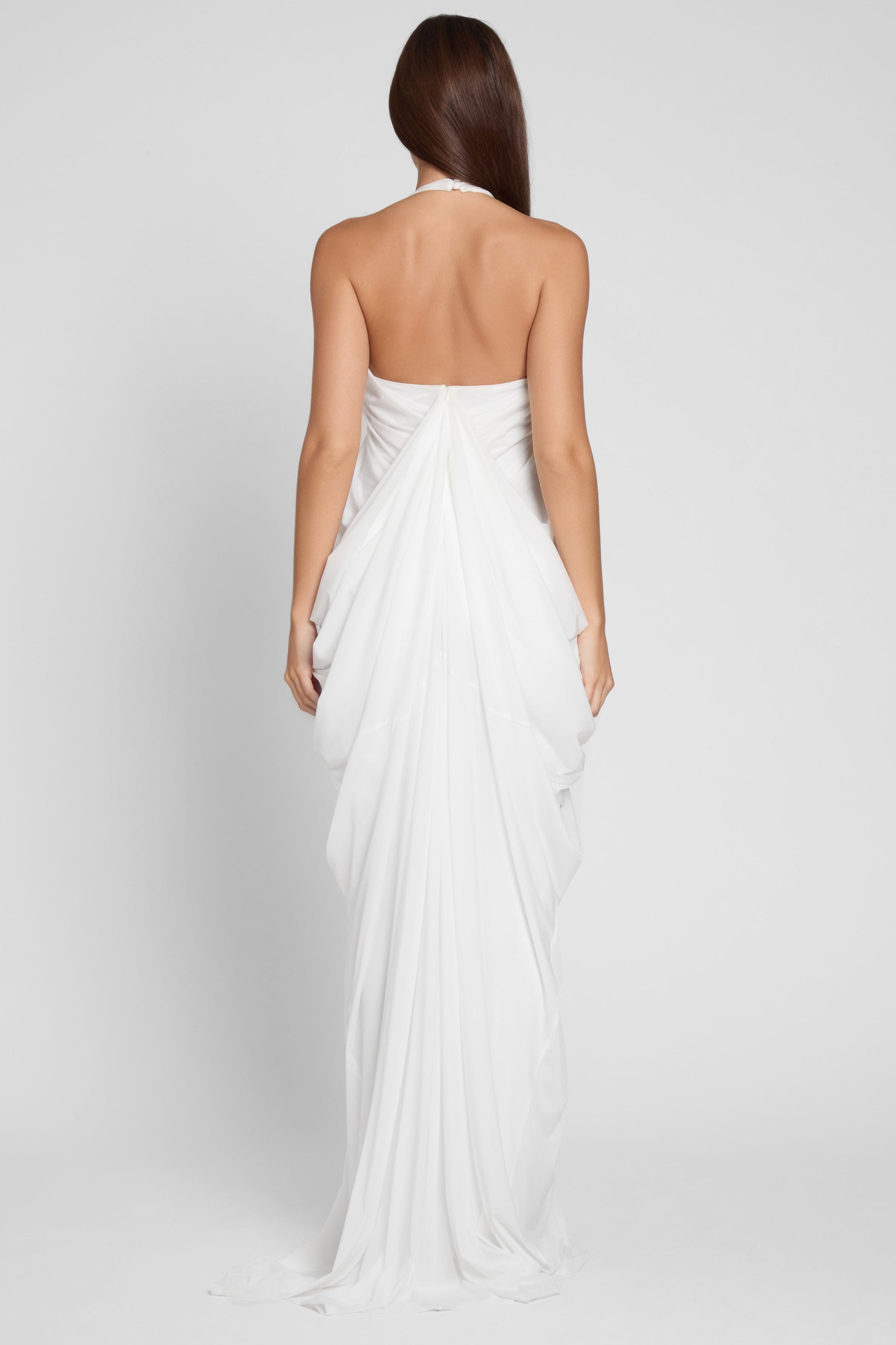 Model is wearing Cascade Drape Gown in White, back view.