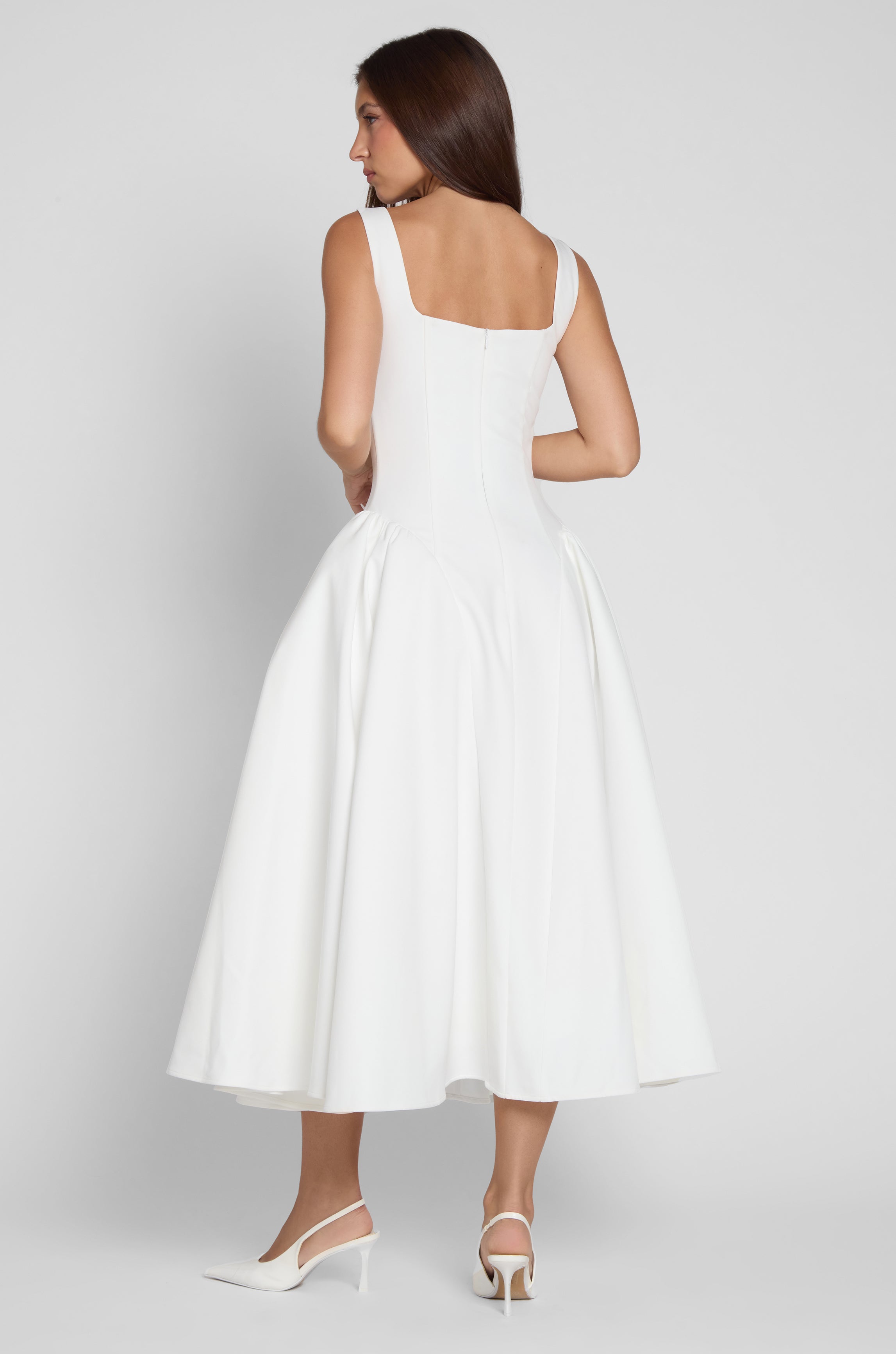 Model is wearing Chloe Corset Midi Dress White, back view.