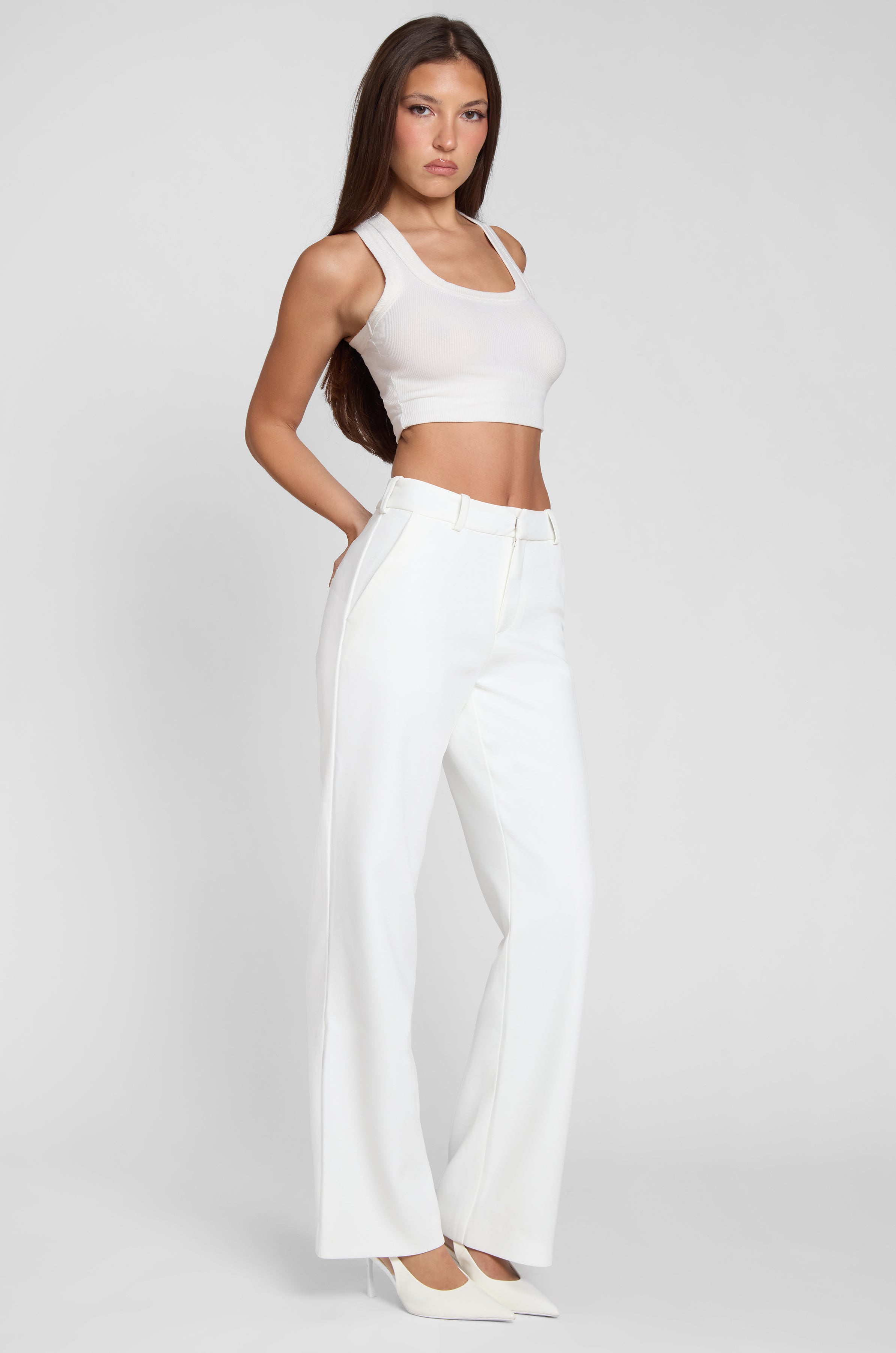 Model wearing Classic Column Straight Trousers in White, side view.