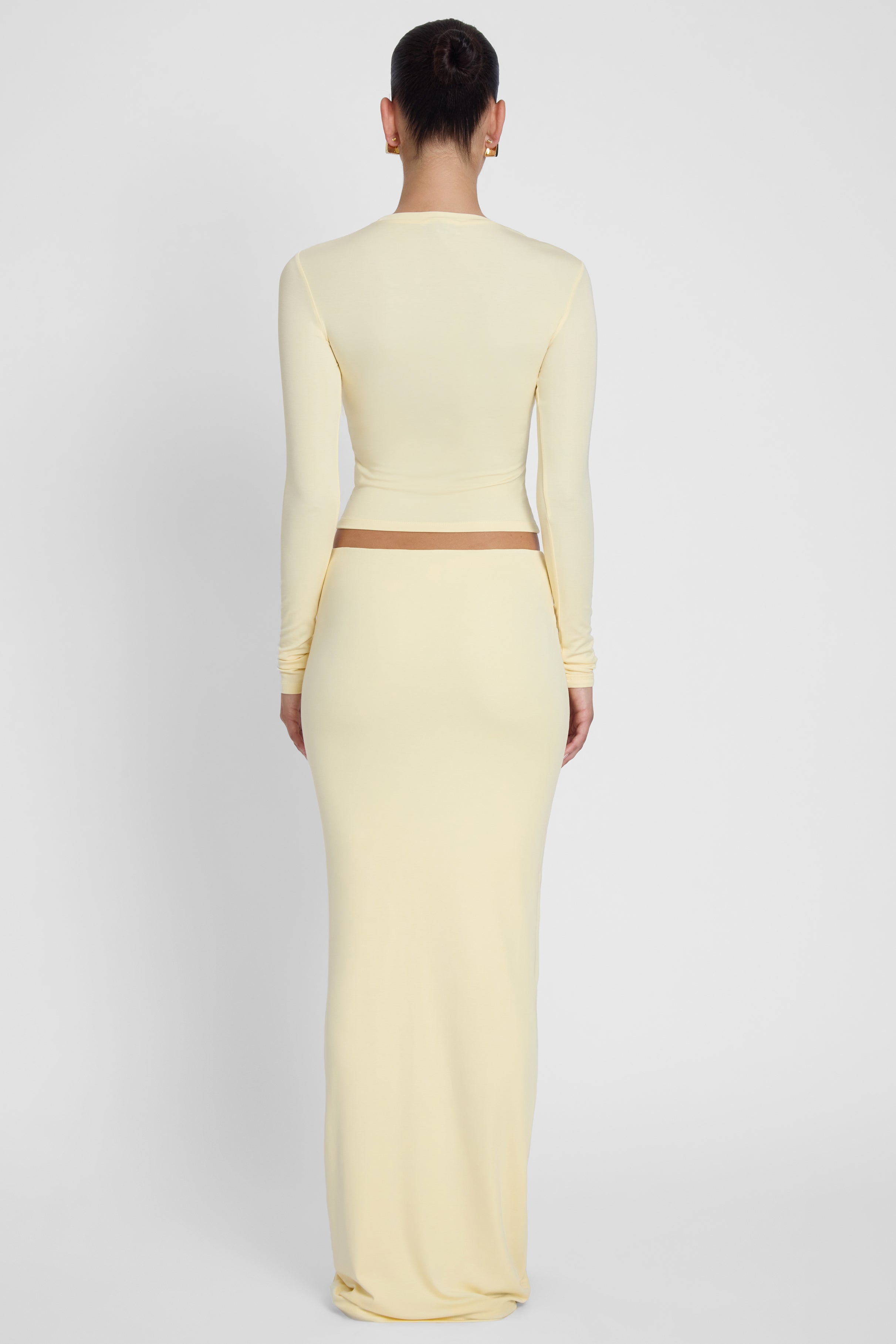 Model is wearing Everyday Jersey Maxi Skirt Yellow, back view.