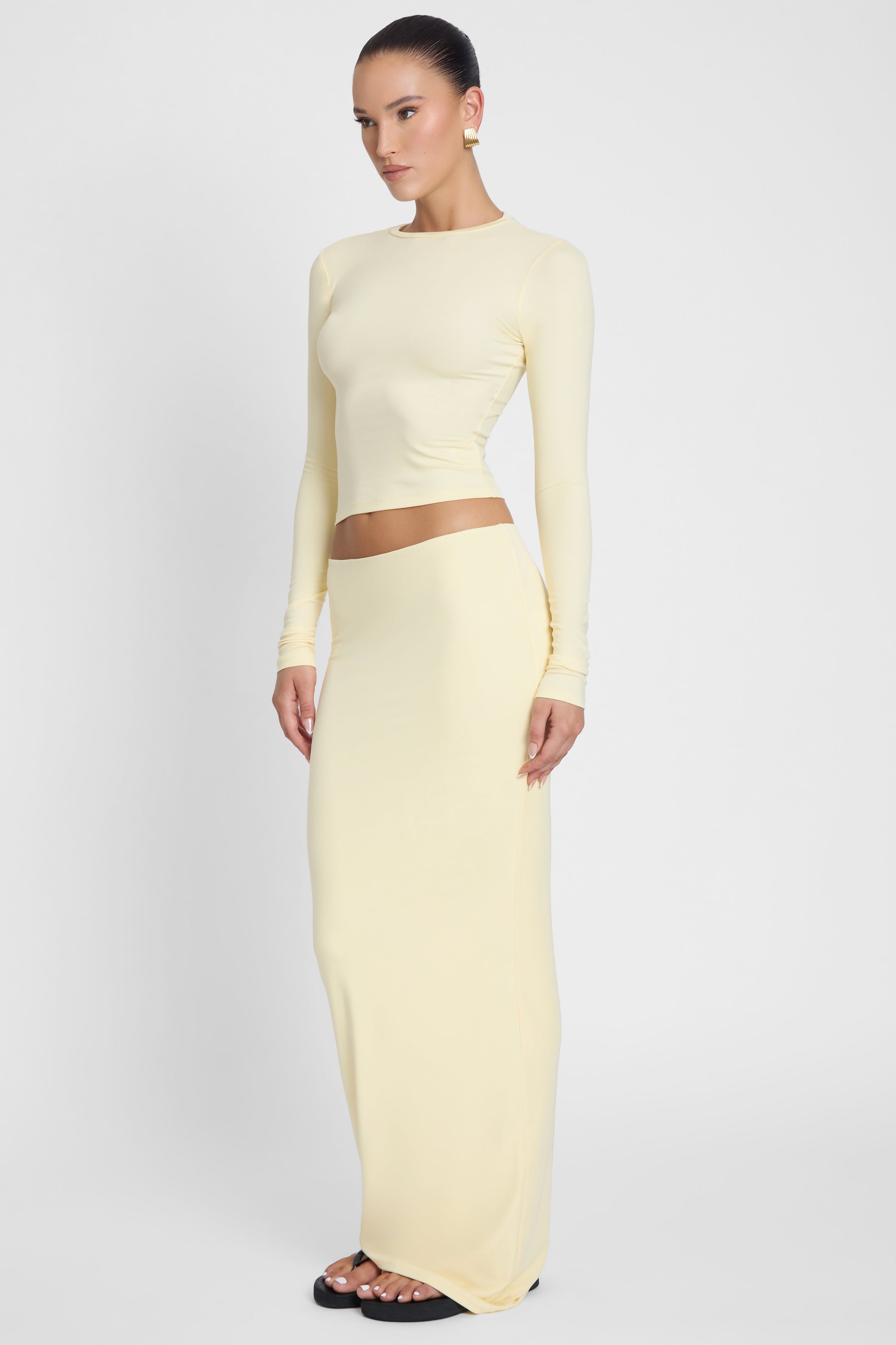 Model is wearing Everyday Jersey Maxi Skirt Yellow, side view.
