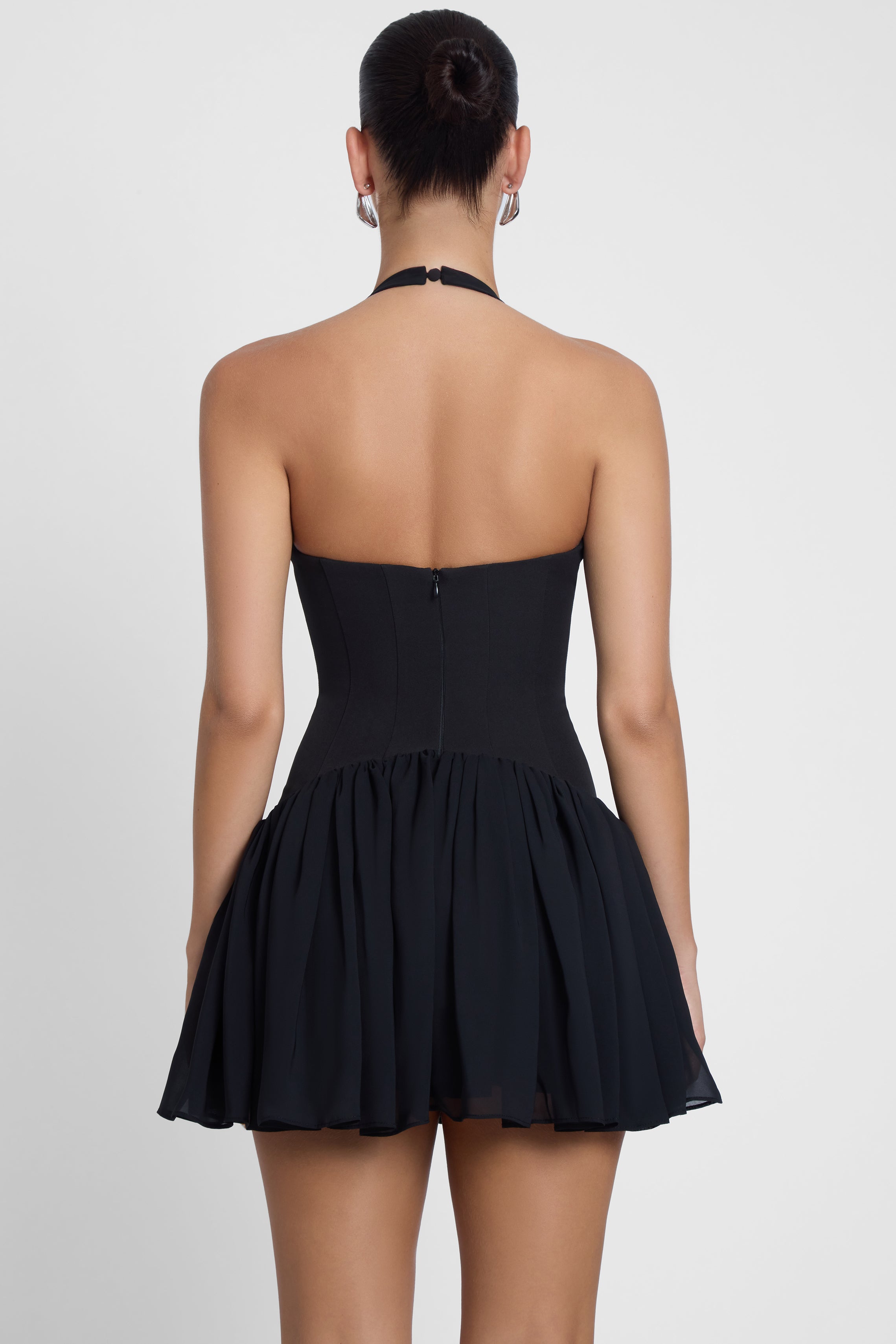 Model is wearing Harper Corset Mini Dress Black, back view.