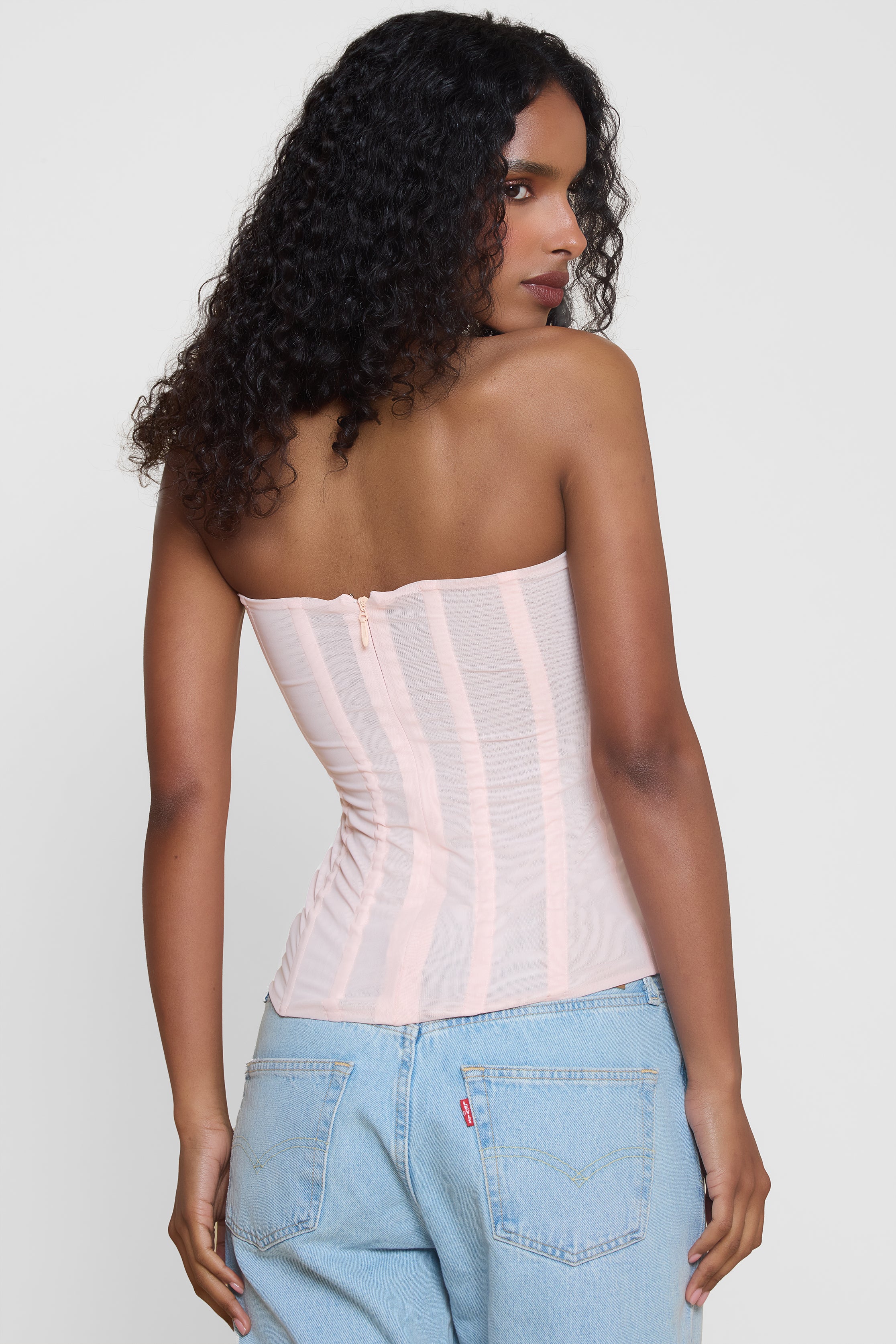 Model wearing Muse Mesh Corset Top in Pink, back view.