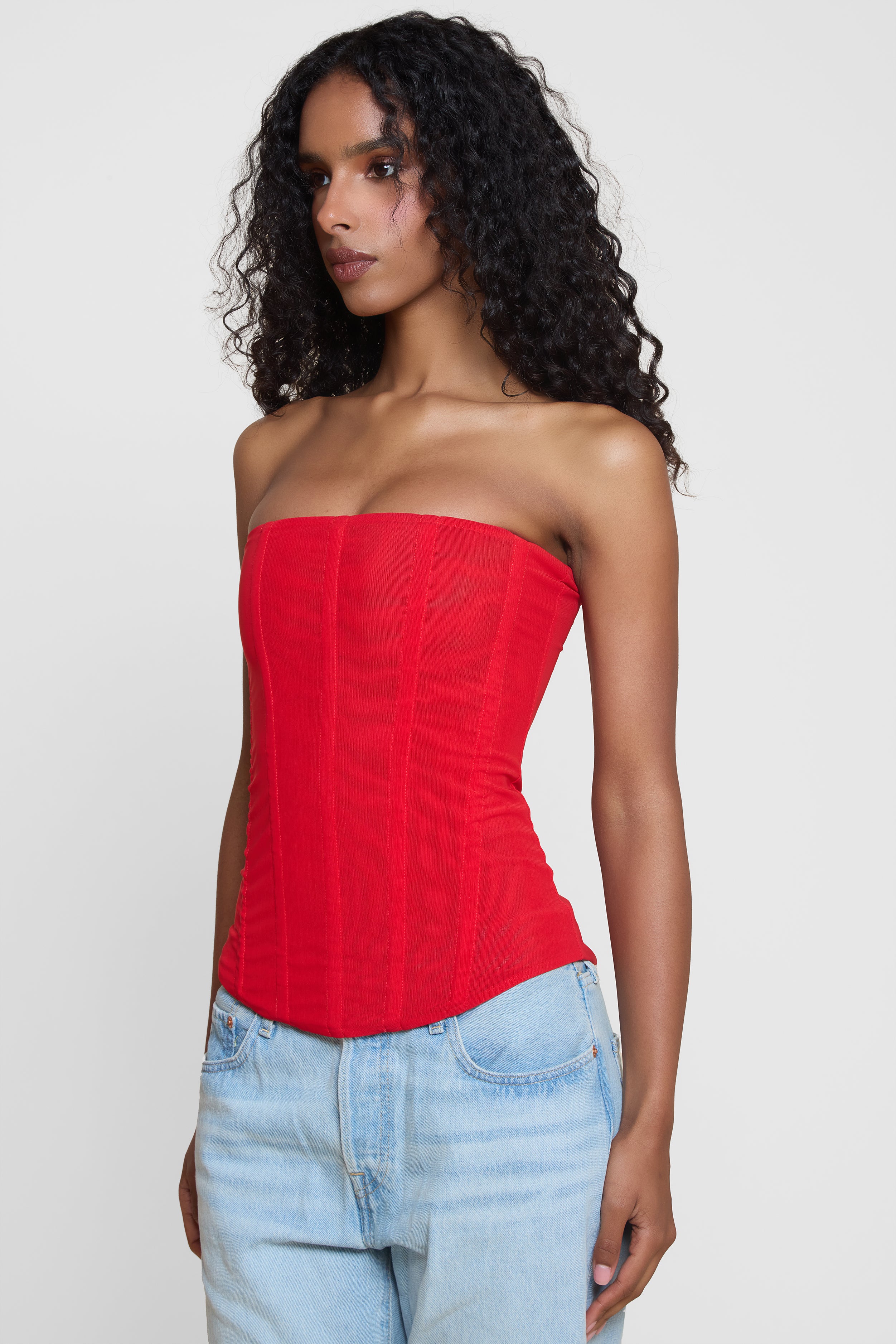 Model wearing Muse Mesh Corset Top in Red, side view.