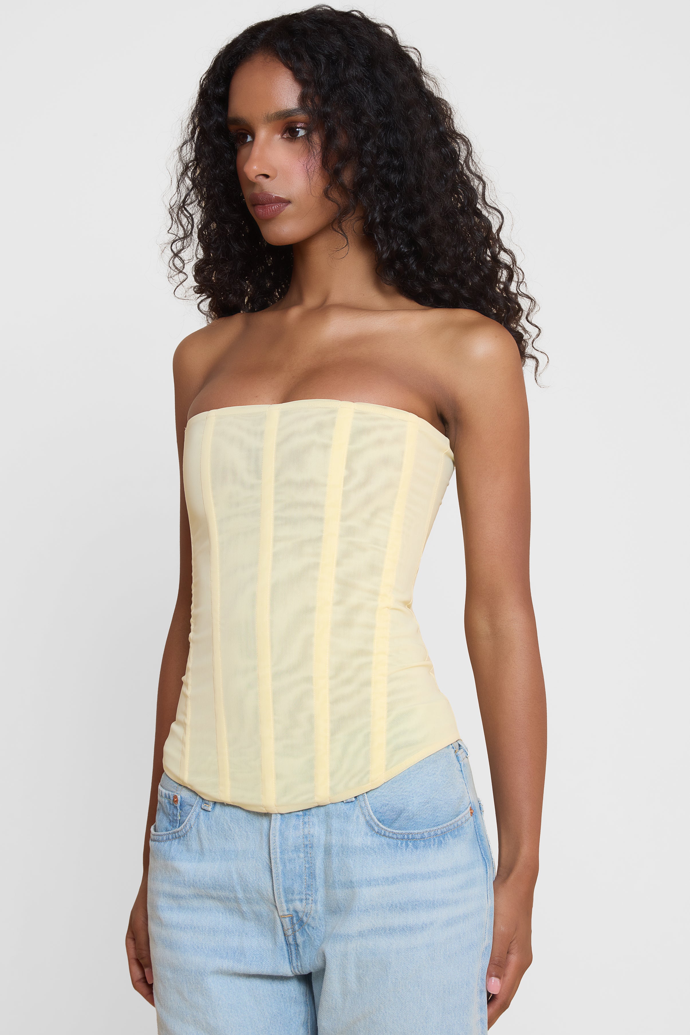 Model wearing Muse Mesh Corset Top in Yellow, side view.
