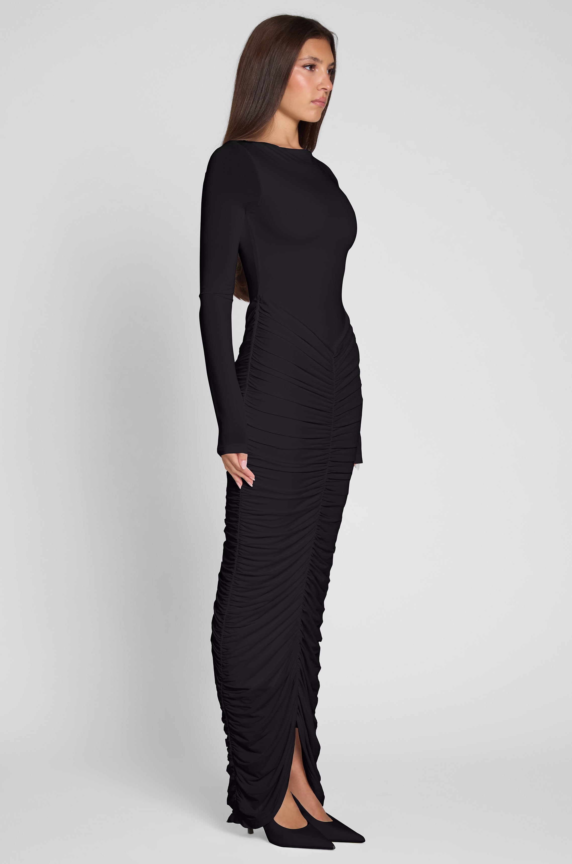 Model is wearing Rhea Ruche Maxi Dress in Black, side view.