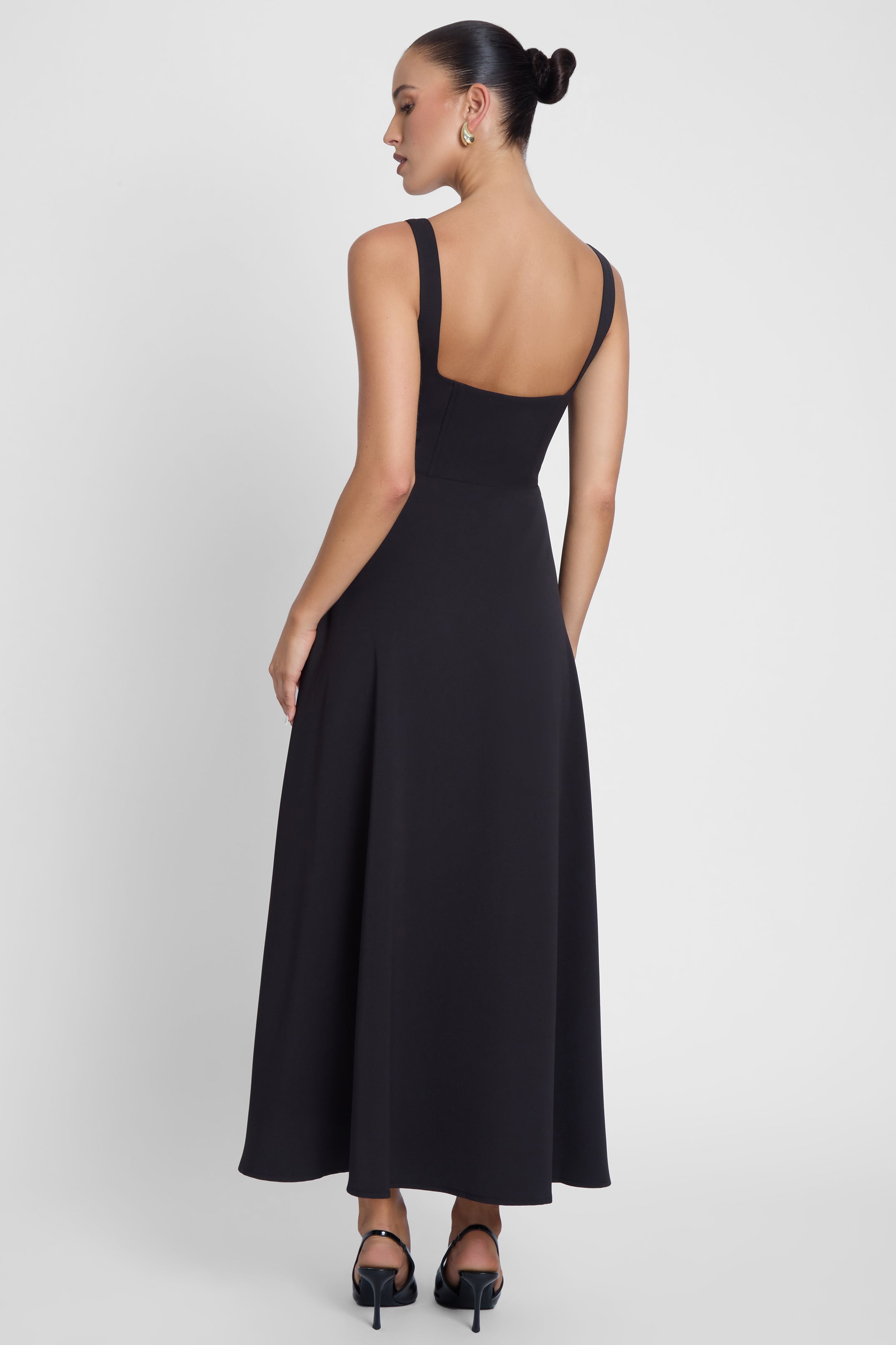 Model is wearing Serenity Square Neck Corset Midi Dress Black, back view.