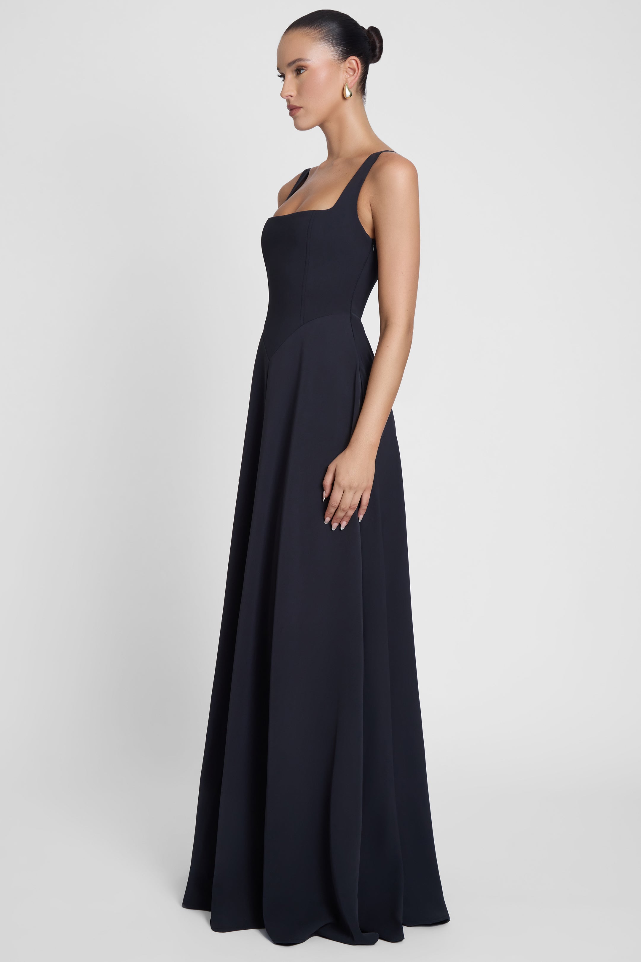 Model is wearing Siren Square Neck Corset Maxi Dress Black, side view.