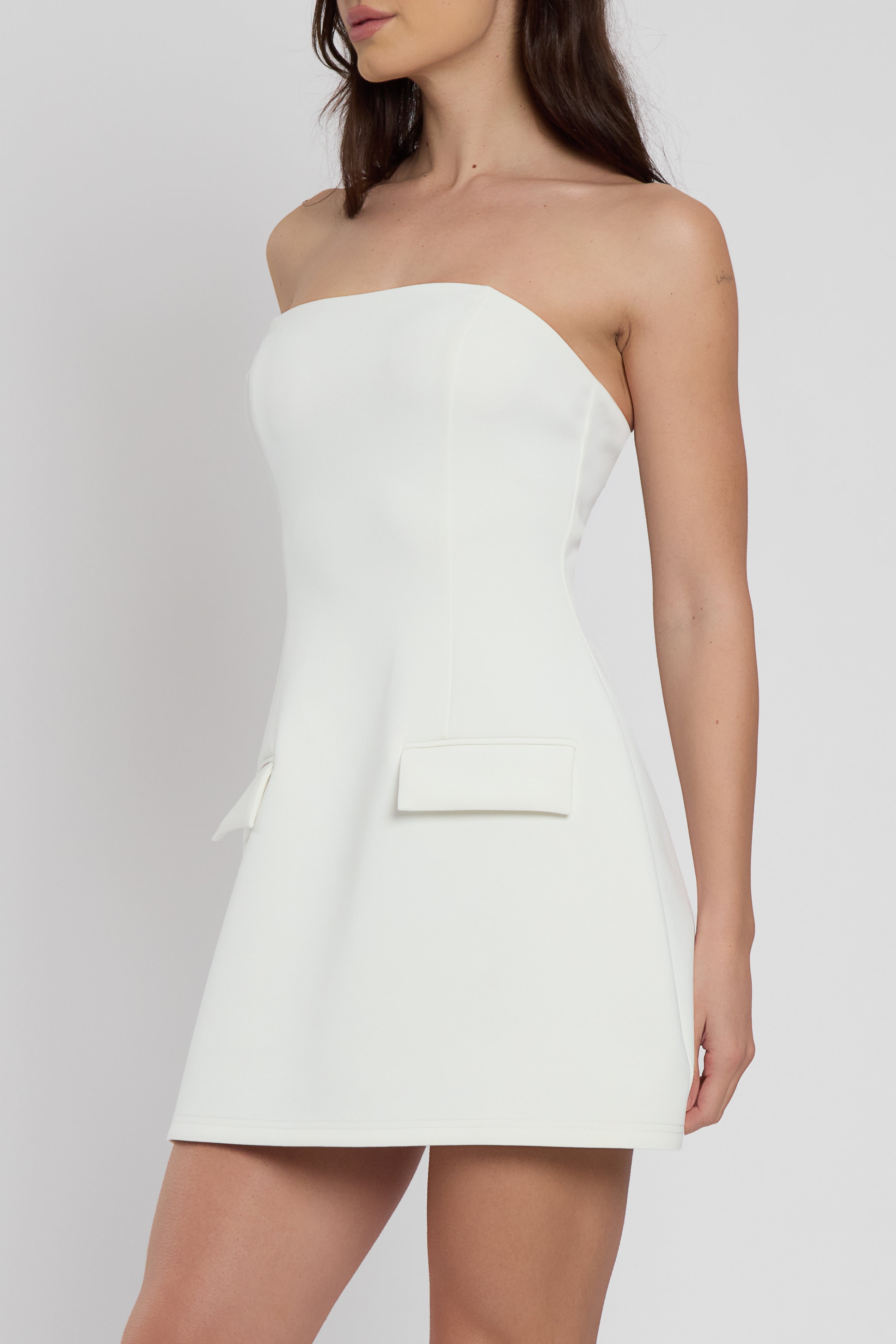 Model wearing Solene Strapless Pocket Mini Dress in White, side view.