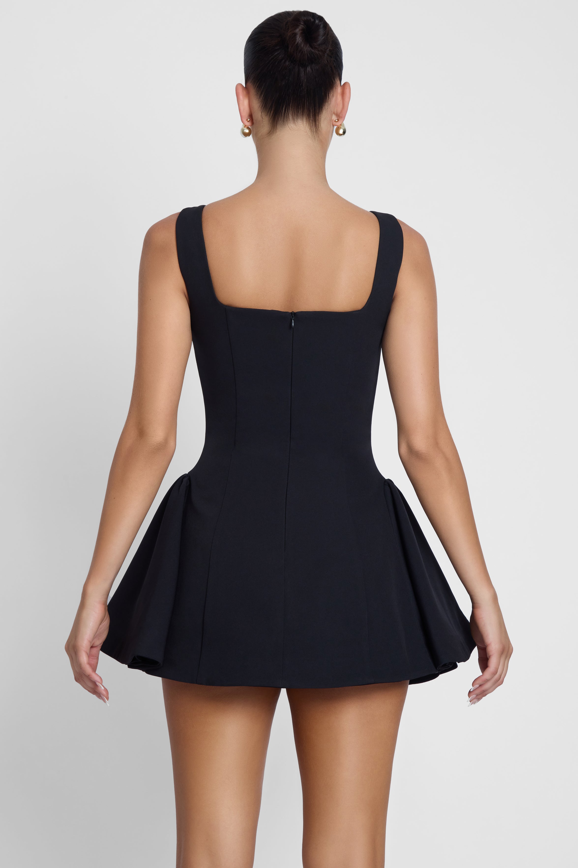 Model is wearing Ysabelle Babydoll Corset Mini Dress Black, back view.